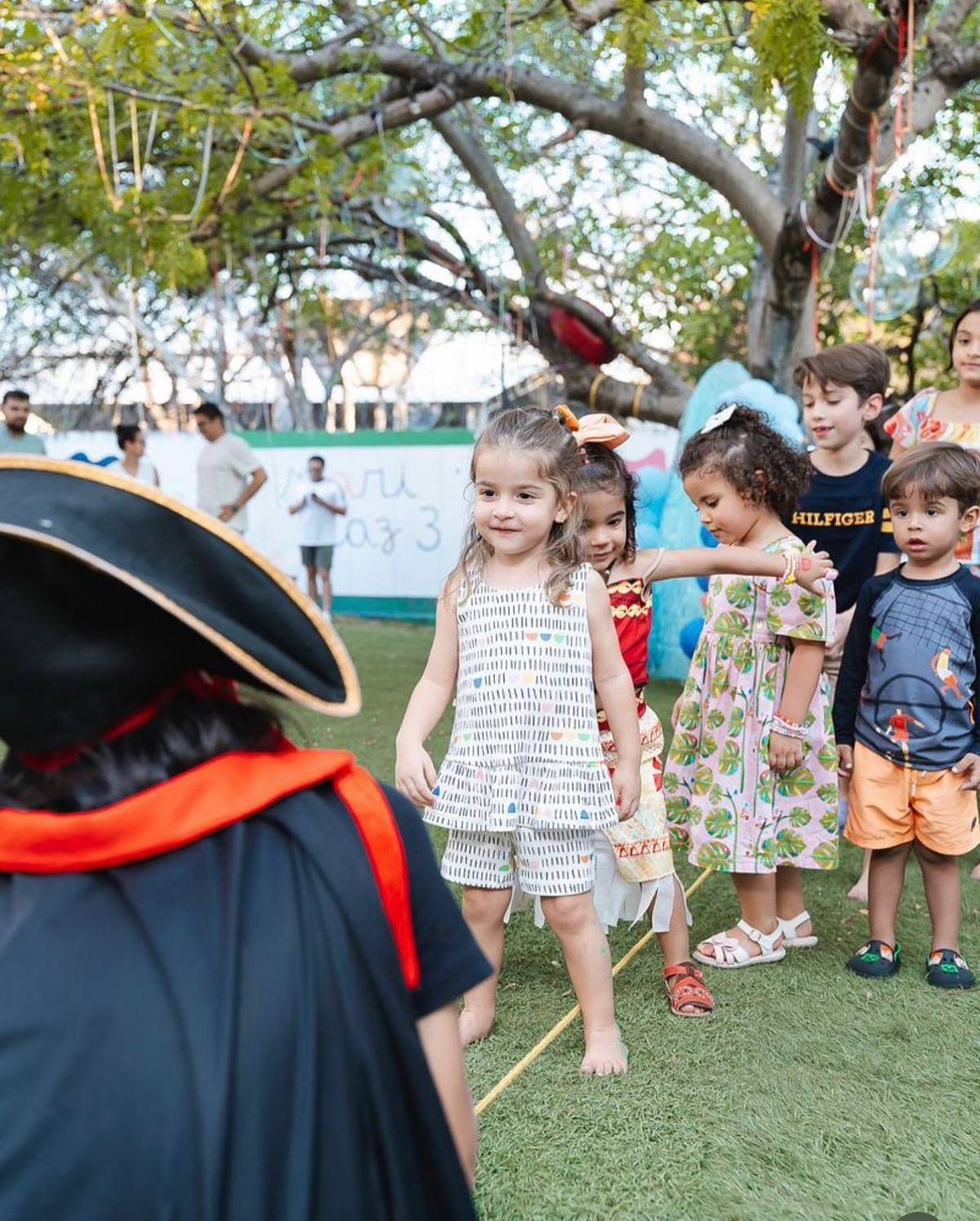 Crianças brincando sob a árvore no quintal do Doce Aprender em uma festa de aniversário