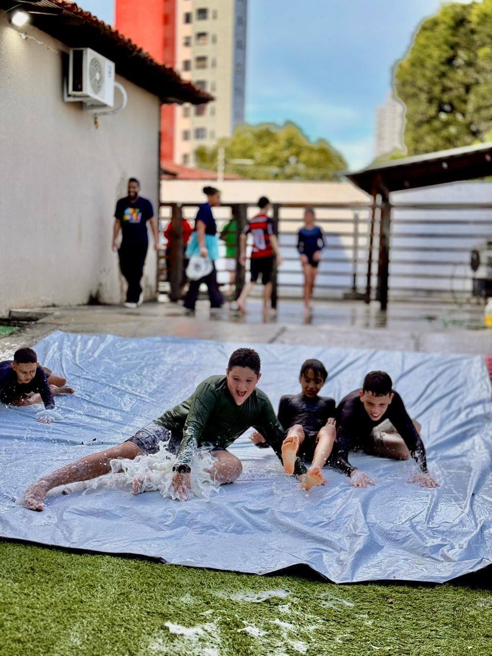 Crianças brincando no escorrega de espuma no quintal do Doce Aprender